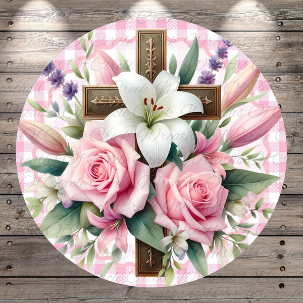 A round floral arrangement with a cross and lilies, set against a pink and white checkered background.