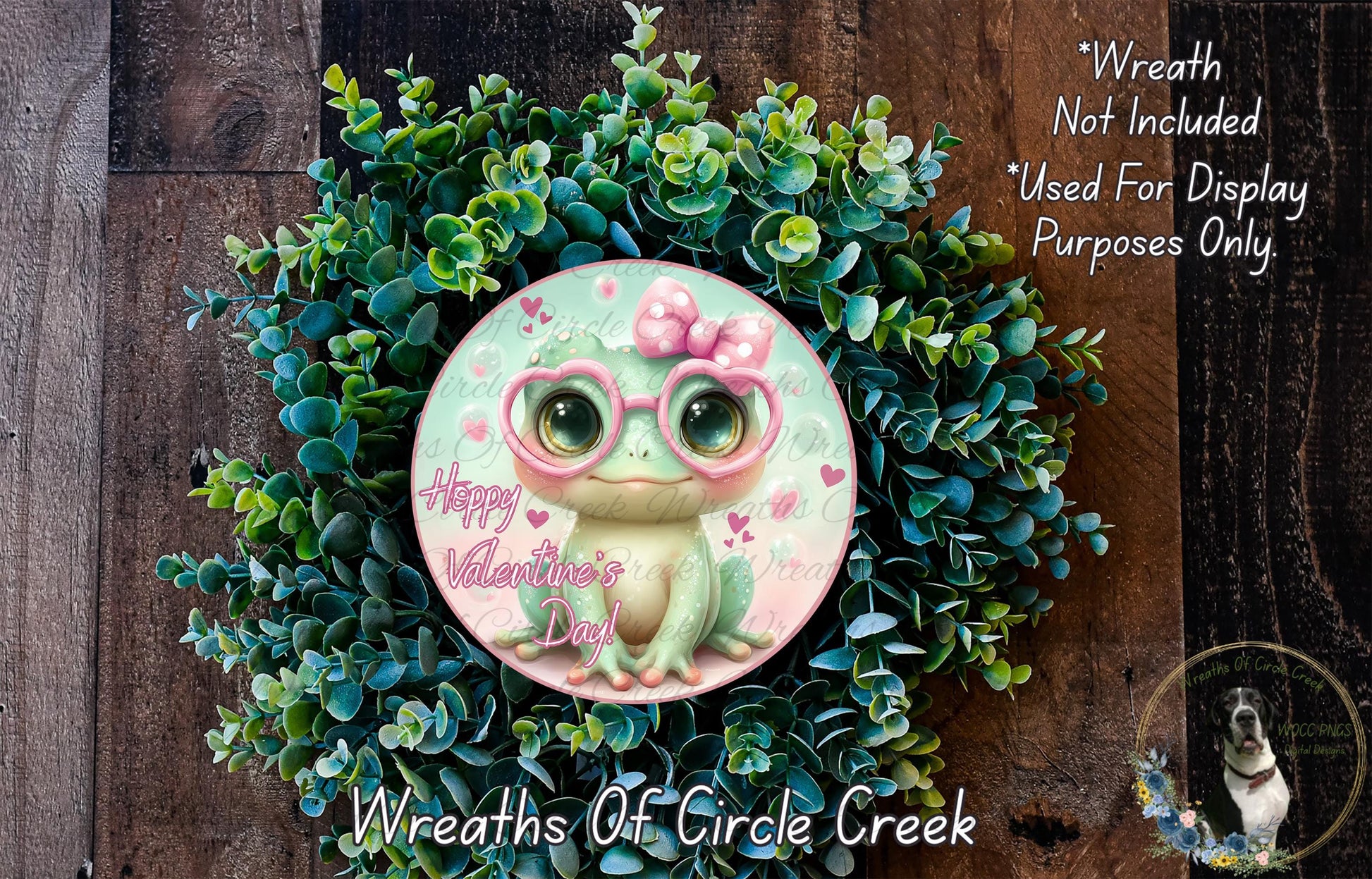 A wreath made of green leaves and flowers, with a small frog wearing pink glasses and the text "Happy Valentine's Day" on it.
