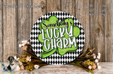 a circular sign with the text "SOMEBODY'S LUCKY SHARM" written on it, surrounded by a black and white checkered pattern and a green shamrock. The sign is placed on a wooden surface, with a wreath of flowers and greenery to the side.