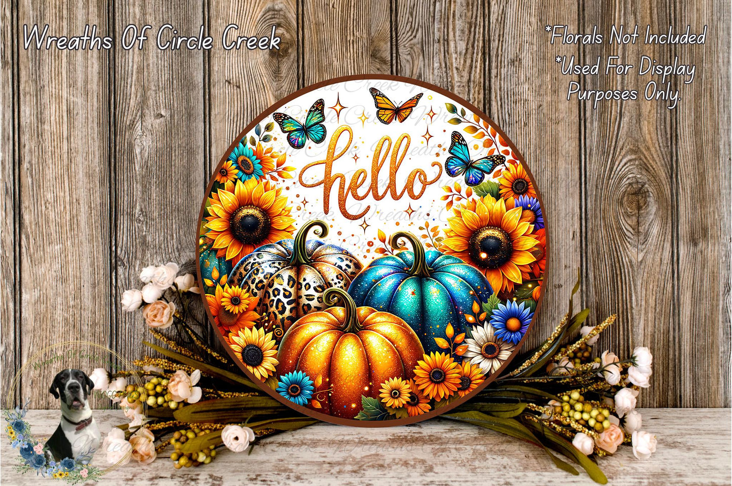 A decorative wreath with a floral design, featuring pumpkins, sunflowers, and butterflies. The word "Hello" is written on the wreath. The wreath is placed on a wooden surface, surrounded by flowers.