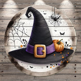 A witch's hat with a purple band and a gold buckle, along with a small orange pumpkin, is displayed on a wooden surface.