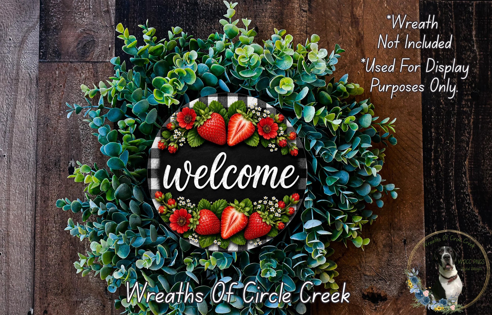 a wreath with a welcome sign in the center, surrounded by various green and red flowers, including strawberries. The wreath is displayed on a wooden surface, and there is a small dog in the bottom right corner of the image.