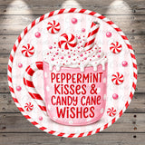 A pink mug filled with whipped cream and surrounded by red and white striped candy canes, with the text "Peppermint Kisses & Candy Cane Wishes" written on the mug.