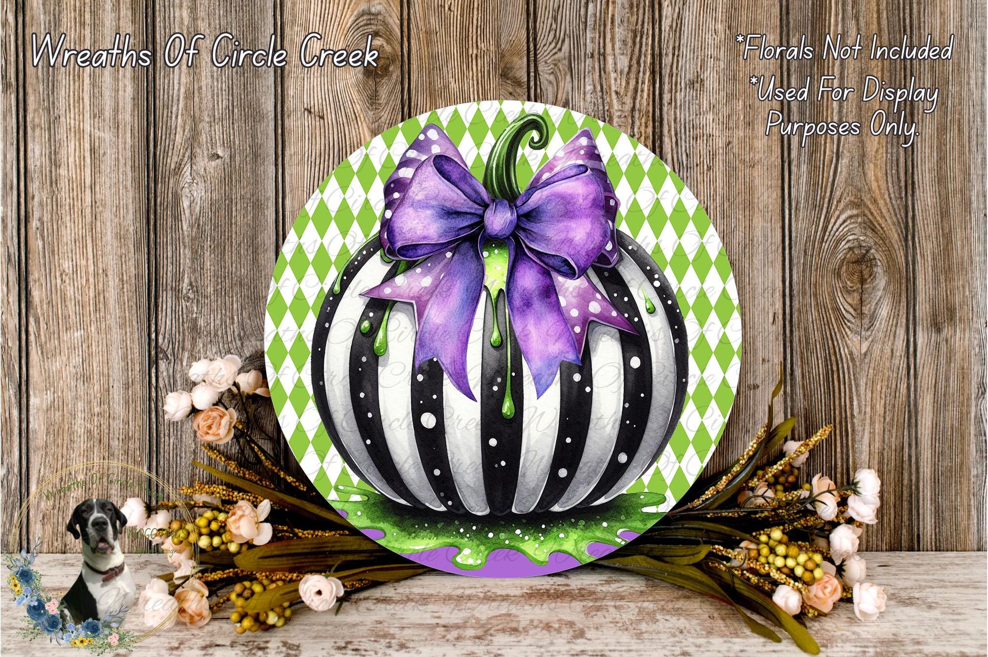 a decorative pumpkin with a purple bow, surrounded by flowers and placed on a wooden surface.