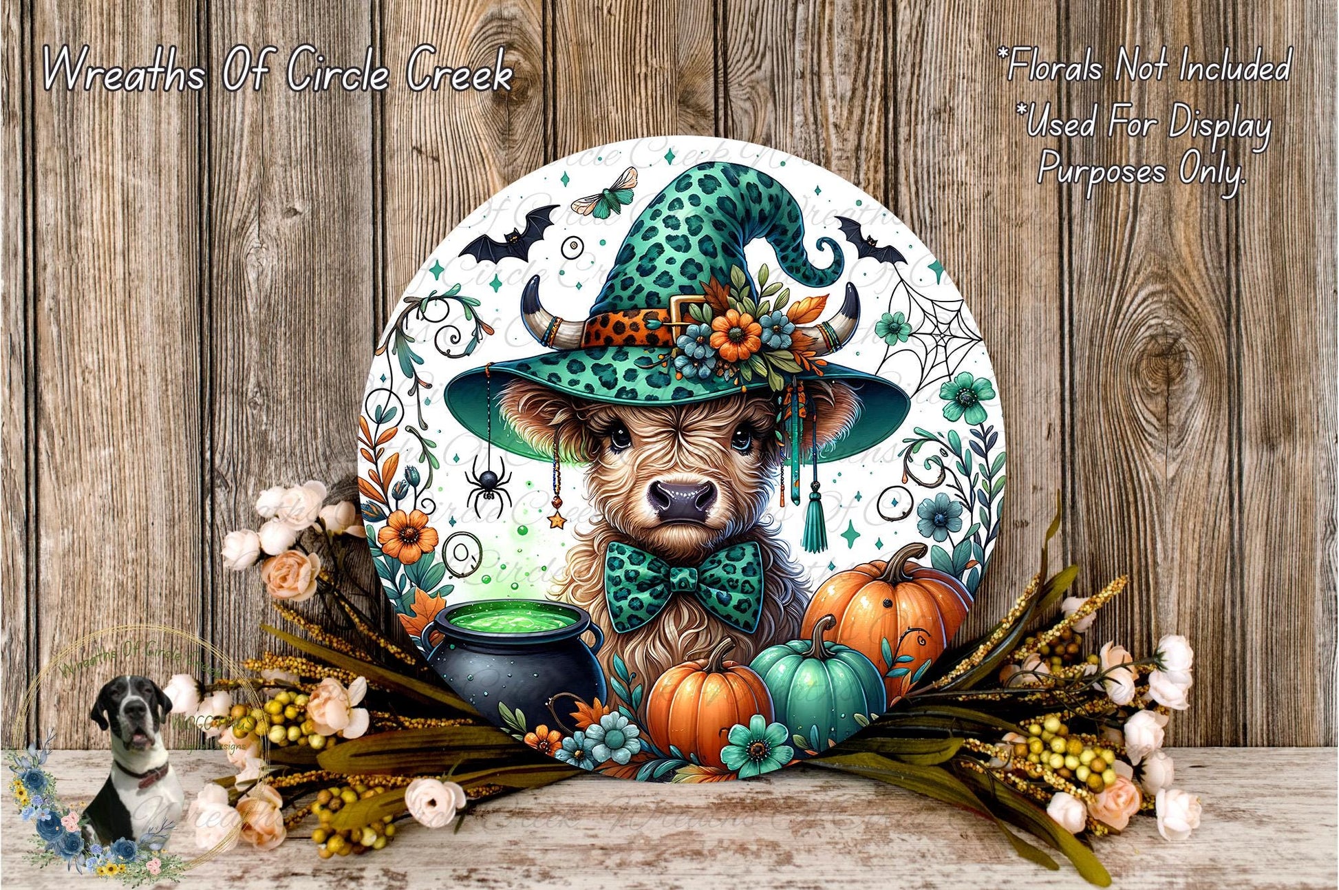 A whimsical illustration of a cow wearing a green witch's hat, surrounded by autumnal elements such as pumpkins, flowers, and a cauldron, all set against a rustic wooden background.