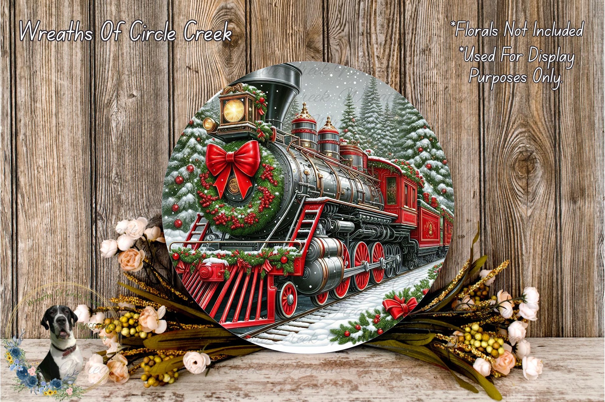A decorative Christmas-themed wreath featuring a red and black steam locomotive surrounded by snow and evergreen trees, with a wreath made of flowers and greenery on a wooden background.