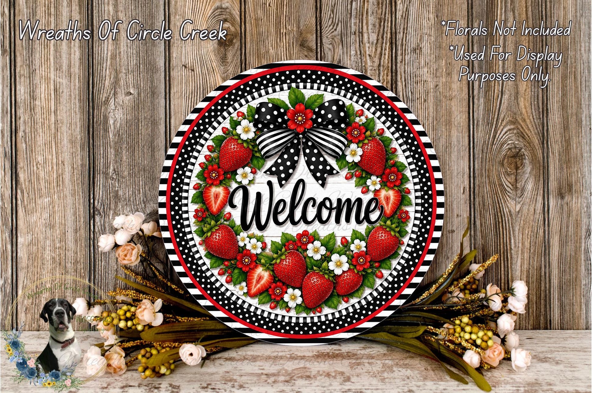 A decorative wreath with a welcoming message, surrounded by flowers and greenery, placed on a wooden surface.