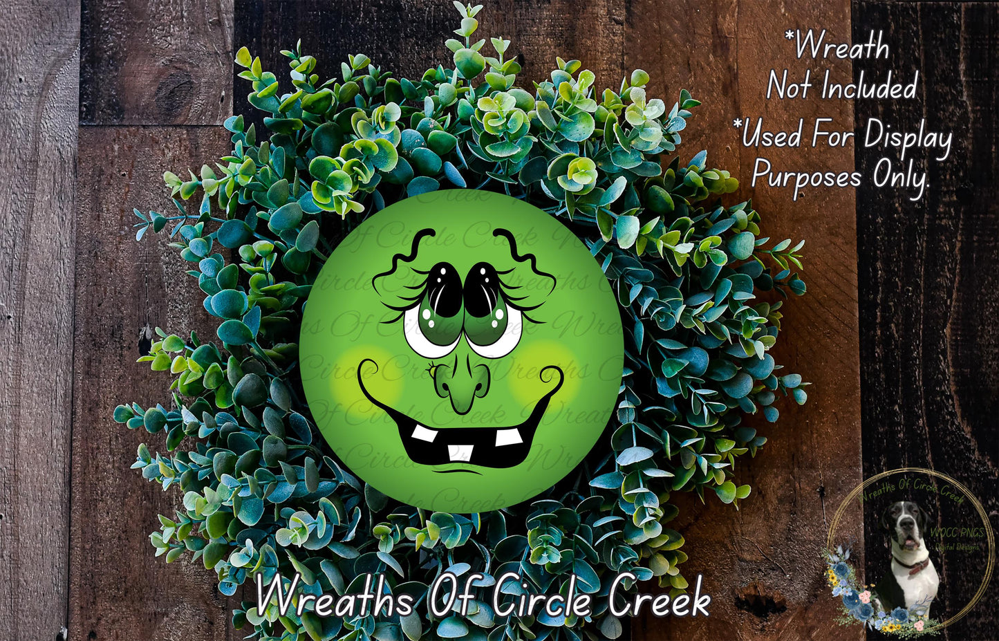A wreath made of green leaves and a large, round, cartoonish face with a big smile and exaggerated features, placed on a wooden surface.