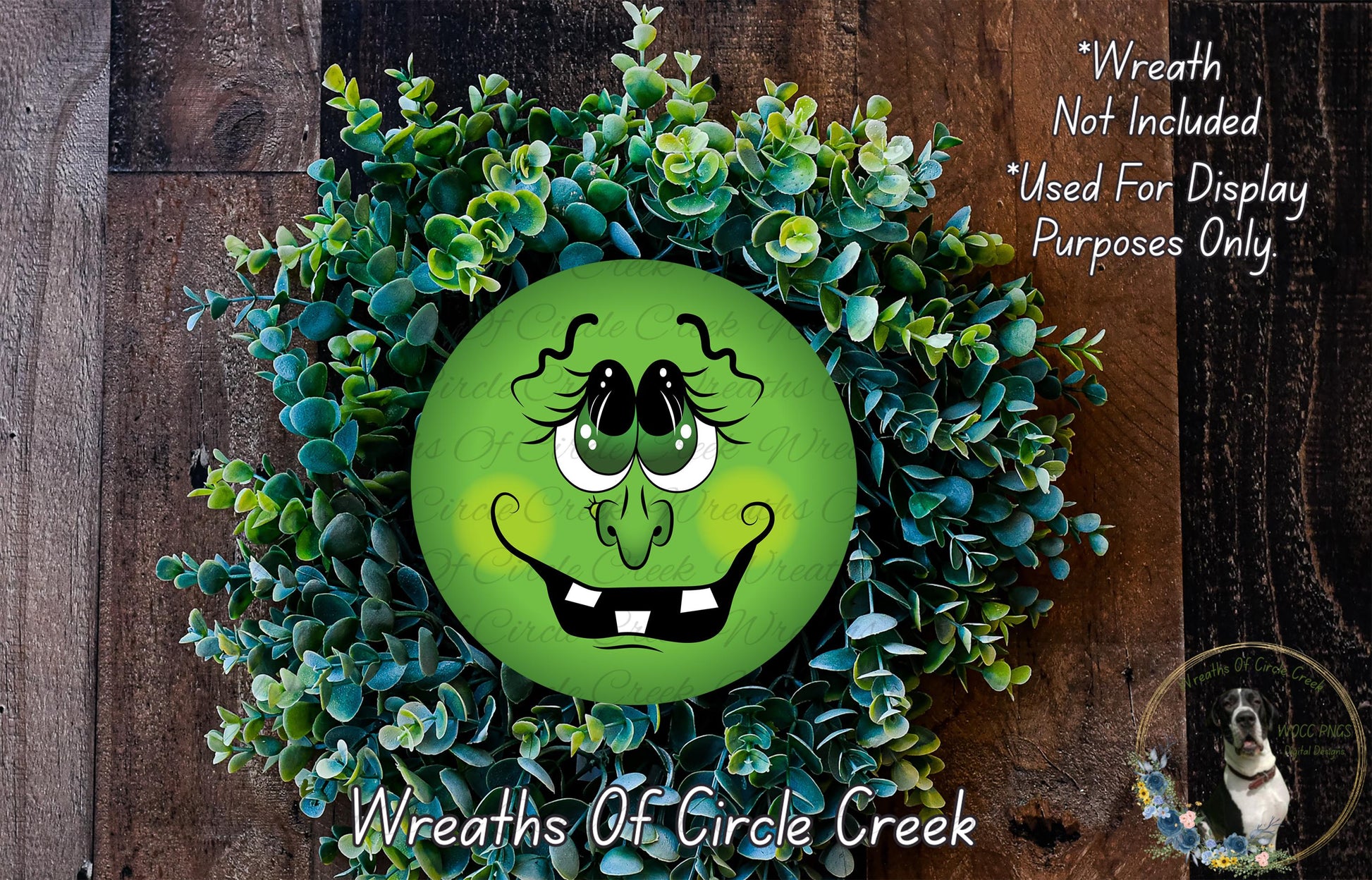 A wreath made of green leaves and a large, round, cartoonish face with a big smile and exaggerated features, placed on a wooden surface.