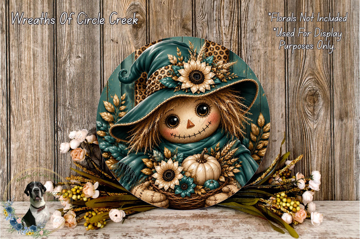 A decorative wreath featuring a scarecrow-like figure with a hat and floral elements, placed on a wooden surface with flowers and greenery.