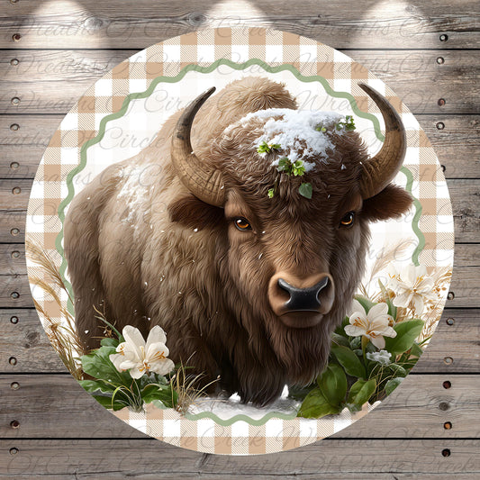 A close-up of a bison with snow on its head, surrounded by flowers and greenery, set against a wooden background.