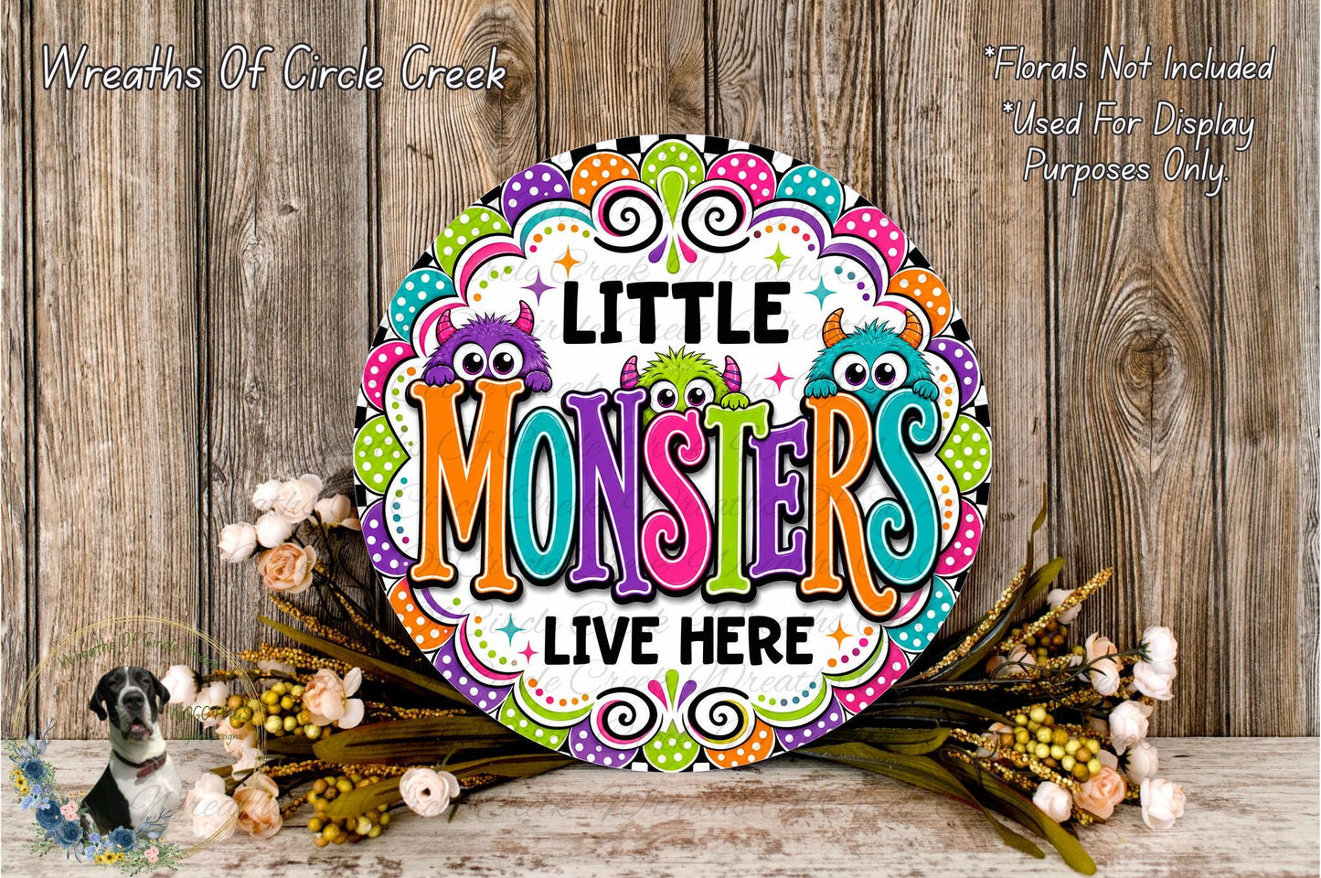 A colorful sign with the text "LITTLE MONSTERS LIVE HERE" surrounded by a decorative border and flowers.