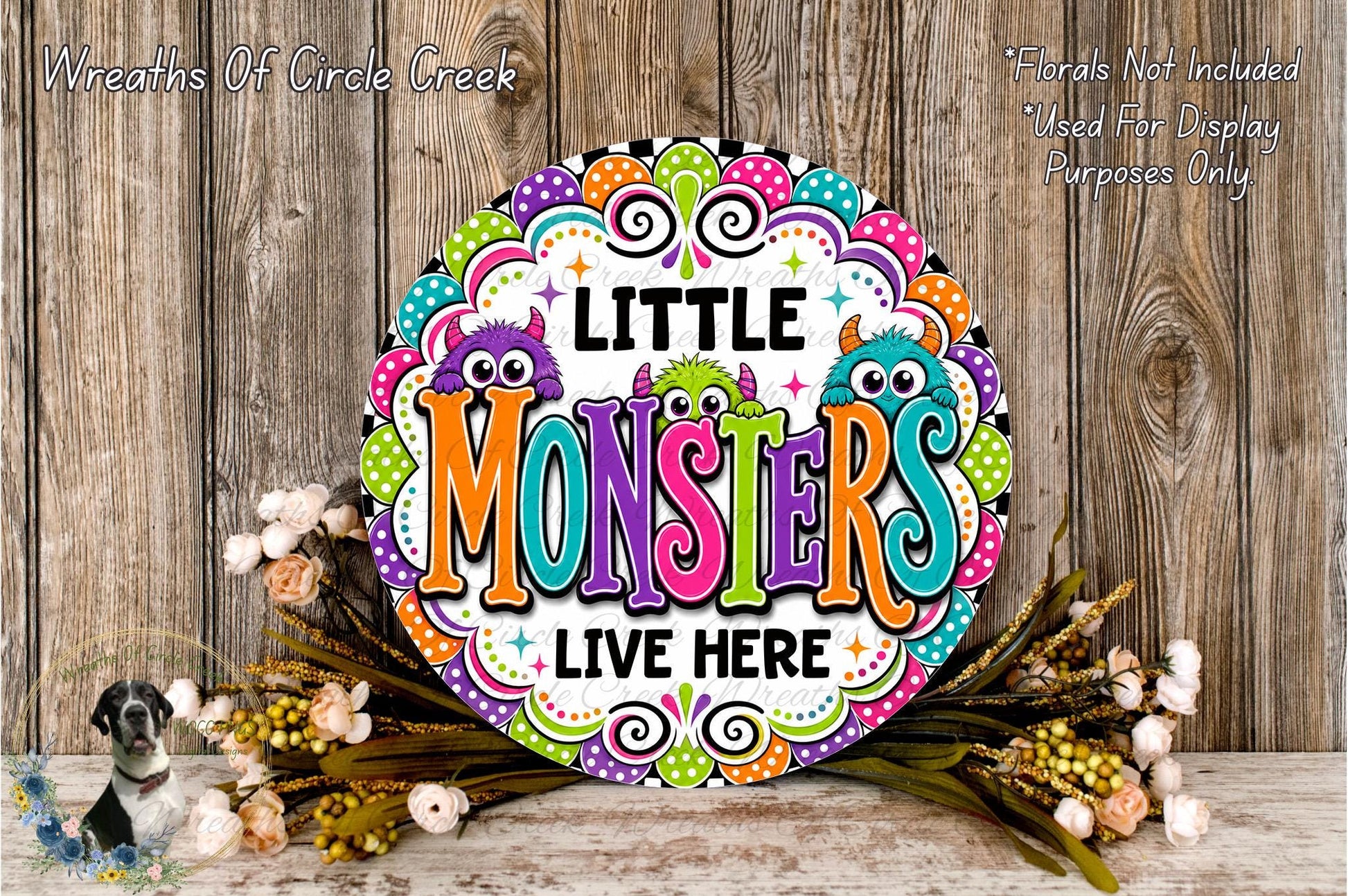 A colorful sign with the text "LITTLE MONSTERS LIVE HERE" surrounded by a decorative border and flowers.