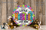A colorful sign with the text "LITTLE MONSTERS LIVE HERE" surrounded by a decorative border and flowers.