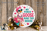 a decorative sign with a cartoon goose wearing sunglasses and a bow, surrounded by flowers and greenery. The sign has the text "My Porch Goose Runs This House" and is placed on a wooden surface.