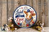 a decorative sign with a cow wearing a patriotic bow, surrounded by flowers and placed on a wooden surface.