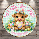A round sign featuring a cartoon cow holding a heart-shaped Easter egg, surrounded by flowers and Easter eggs, with the text "The golden bunny bakery" and "Hop into something delicious" written around the sign.