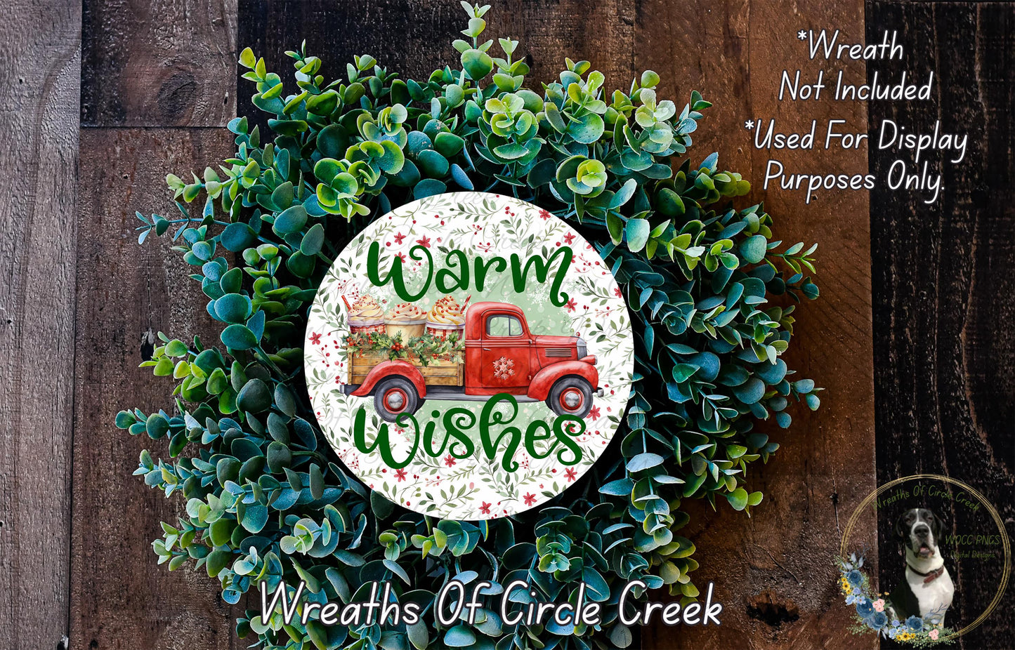 a wreath with a red truck and the text "Warm Wishes" on it, surrounded by green foliage.