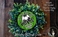 a wreath made of green leaves and a soccer ball, with the text "If we're not home, check the field" displayed on it.