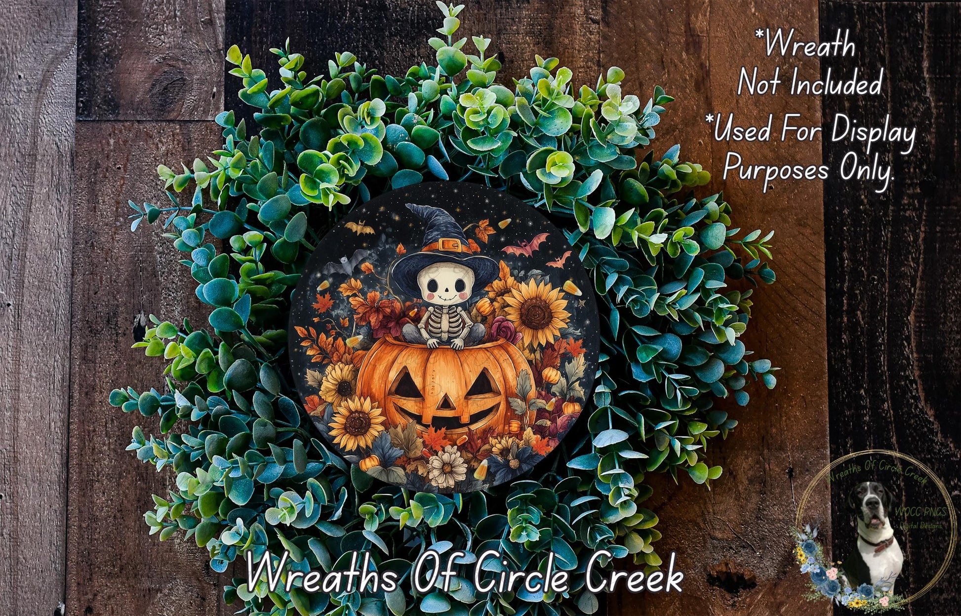 A Halloween-themed wreath made of green foliage and a pumpkin with a skeleton on it, placed on a wooden surface.