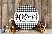 a circular sign with the text "Welcome Just Kidding. Please Leave." surrounded by a floral arrangement and a wooden background.