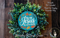 a wreath made of green leaves and a wooden sign with the text "Fall for Jesus he never leaves" against a wooden background.