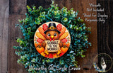 A wreath made of green leaves and a turkey wearing a hat, with the text "GOBBLE TIL YOU WOBBLE!" displayed on it.