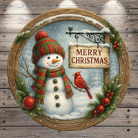 A snowman wearing a red and green striped scarf, holding a sign that says "Merry Christmas", with a red cardinal perched on a branch and red berries on the snowman's body.