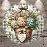 A round wooden plaque with a wicker basket filled with colorful flowers, including hydrangeas and daisies, and a heart-shaped sign that says "Happy Mother's Day".