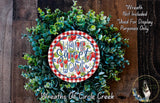 a wreath made of green leaves and a red and white plate with the text "Home Sweet Home" on it, placed on a wooden surface.