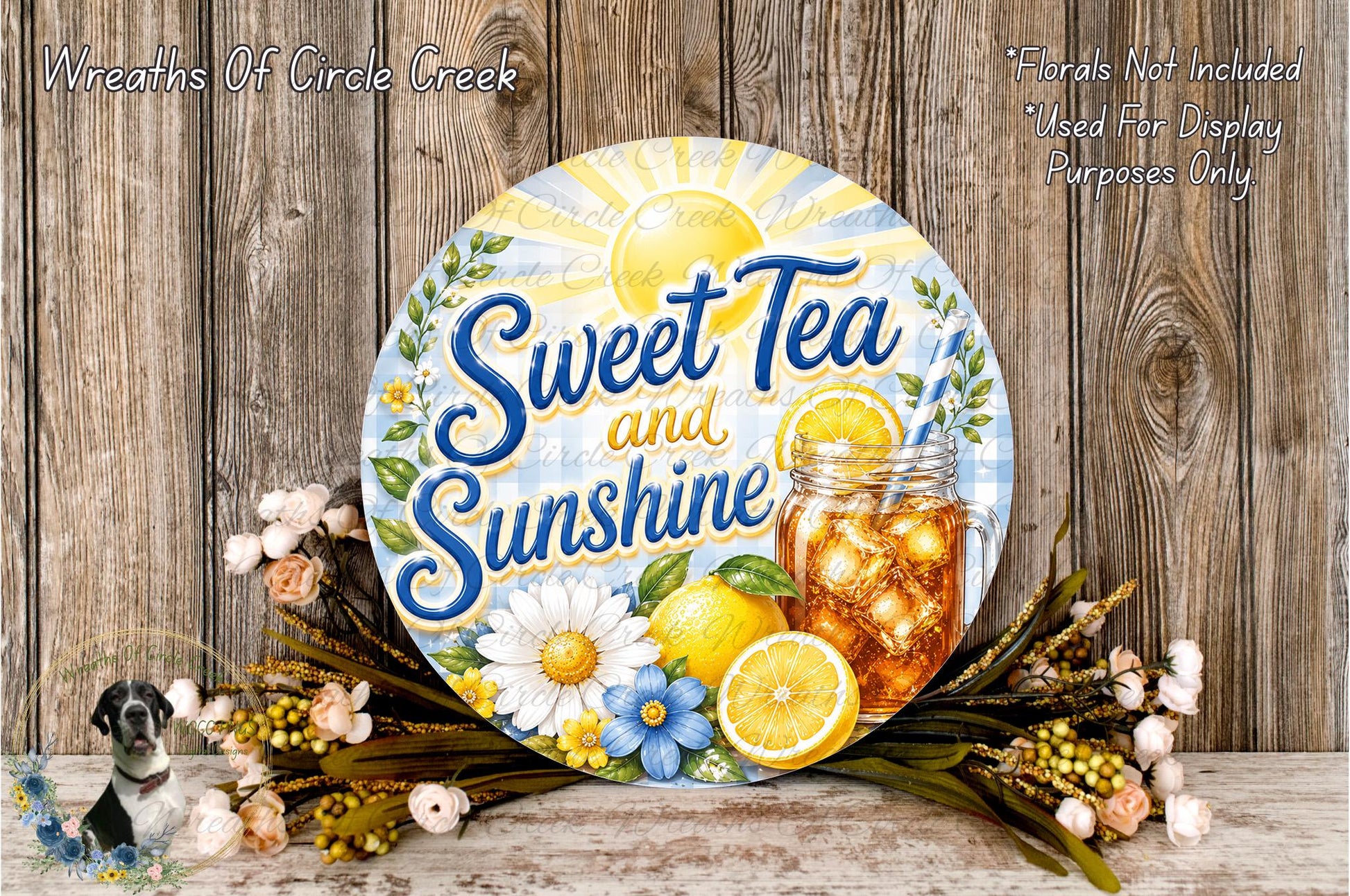 a round sign with the text "Sweet Tea and Sunshine" and an illustration of a glass of tea with lemon slices and flowers. The sign is surrounded by a floral arrangement and a wooden background.