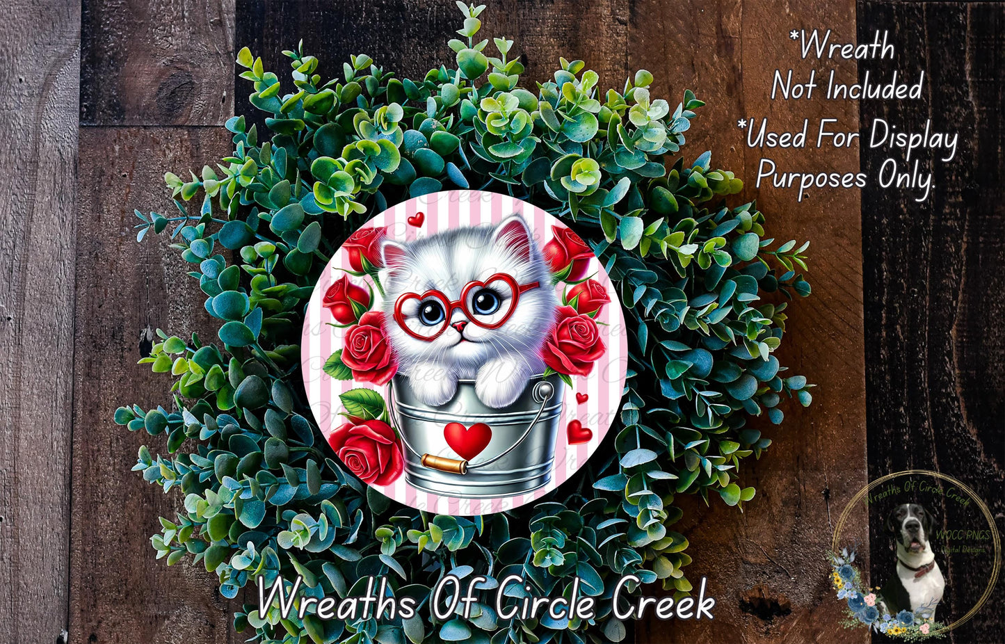 A wreath made of green leaves and red roses, with a small white cat wearing glasses and a heart-shaped bell around its neck, surrounded by a circular design with a heart and a rose.