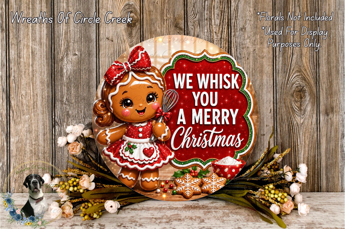 A festive Christmas wreath featuring a gingerbread girl holding a sign that says "We Whisk You a Merry Christmas". The wreath is surrounded by flowers and other holiday decorations, creating a cheerful and seasonal atmosphere.