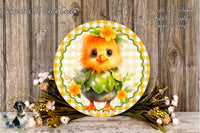 A decorative round plate featuring a cheerful yellow chick wearing a green dress and a flower crown, surrounded by a floral arrangement and a wooden background.