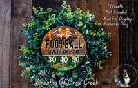 a wreath made of green foliage and a football, with the text "FOOTBALL and fall y'all" and "310 40 50" displayed on it.