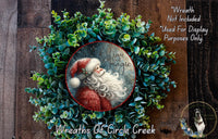 A wreath made of green leaves and a Santa Claus image, with the text "Believe in the magic" written on it.