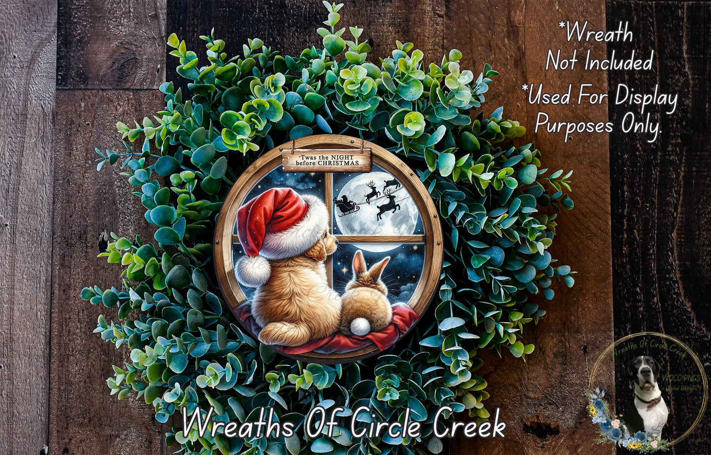 A wreath made of green leaves and featuring a brown rabbit and a white rabbit looking out a window at a full moon and Santa Claus flying on a sleigh.