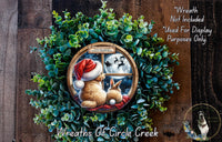 A wreath made of green leaves and featuring a brown rabbit and a white rabbit looking out a window at a full moon and Santa Claus flying on a sleigh.
