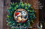 A wreath made of green leaves and featuring a brown rabbit and a white rabbit looking out a window at a full moon and Santa Claus flying on a sleigh.
