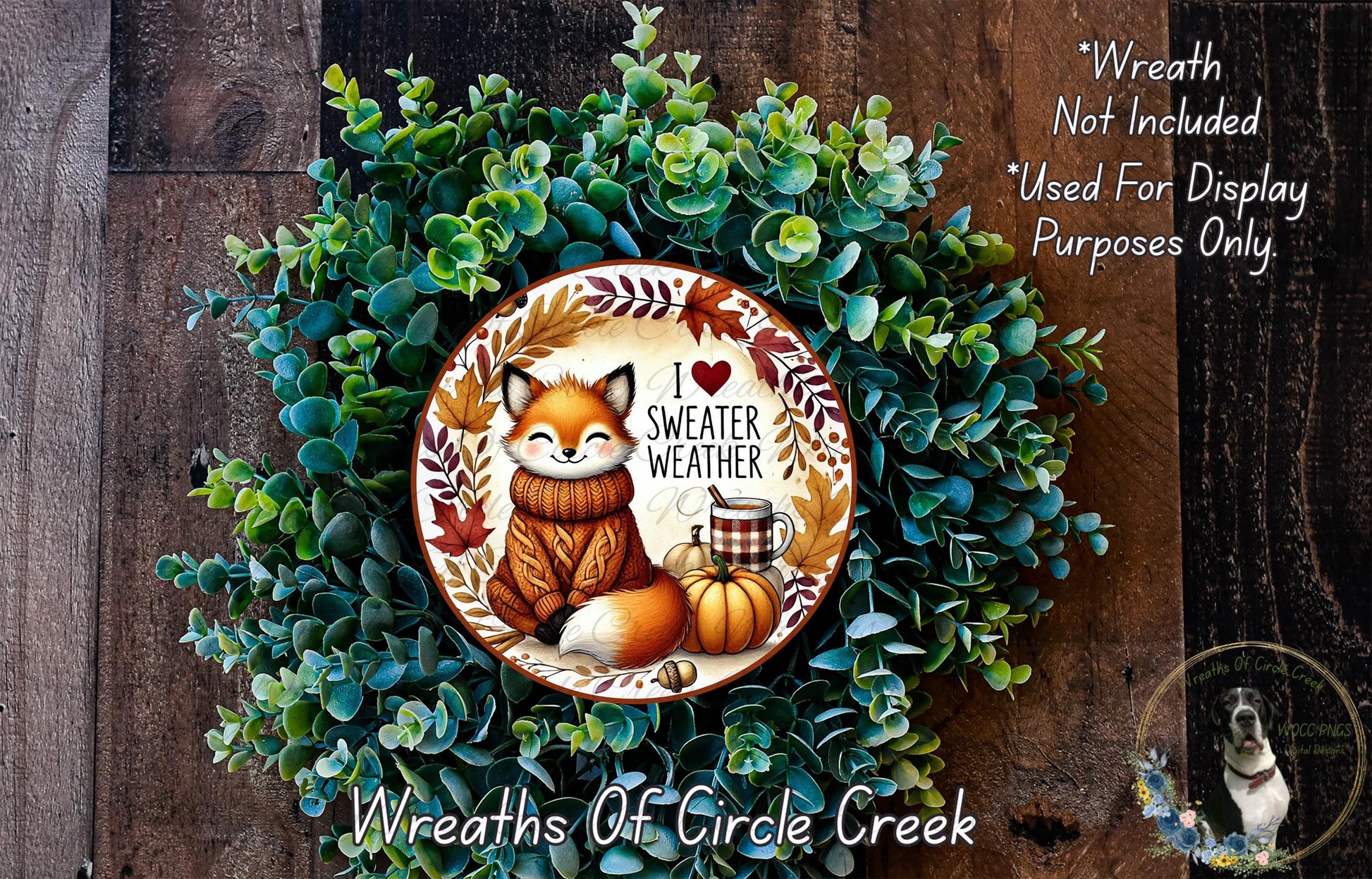 A wreath made of green foliage and featuring a fox wearing a sweater and holding a pumpkin, with the text "I love warmer weather" and "I love sweaters" written on it.