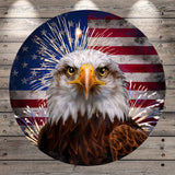 A close-up of a bald eagle with its head turned to the side, set against a backdrop of the American flag with fireworks.