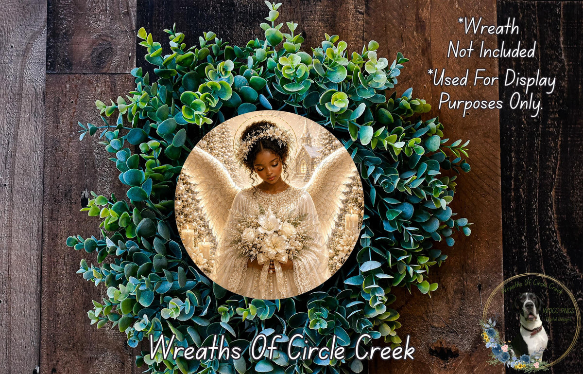 A wreath with a photo of a woman in a white dress and wings, surrounded by green leaves and flowers.