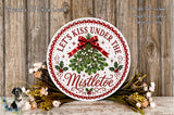 A decorative sign with the text "Let's Kiss Under The Mistletoe" surrounded by a wreath of greenery and flowers, placed on a wooden surface.
