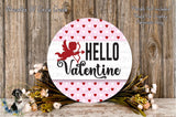 a round sign with the text "Hello Valentine" and a red cherub icon, surrounded by a floral arrangement and a wooden background.