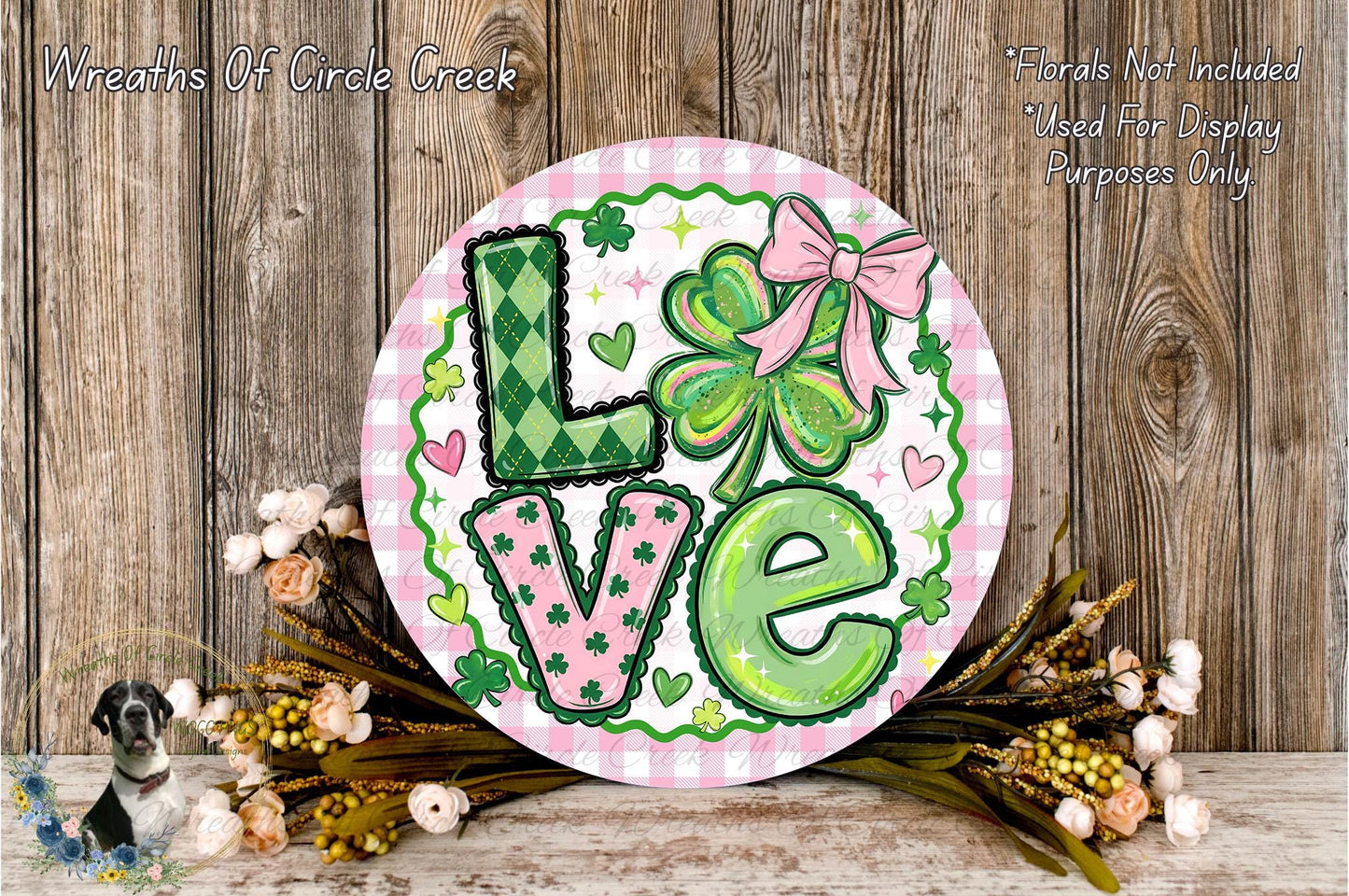 A decorative sign with the word "Love" in large letters, surrounded by various floral elements such as clovers, hearts, and flowers. The sign is placed on a wooden surface, and there are additional floral elements in the background.
