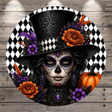 A digital illustration of a woman with a skull-like face, wearing a black top hat and surrounded by colorful flowers, a pumpkin, and a black and white checkered background.
