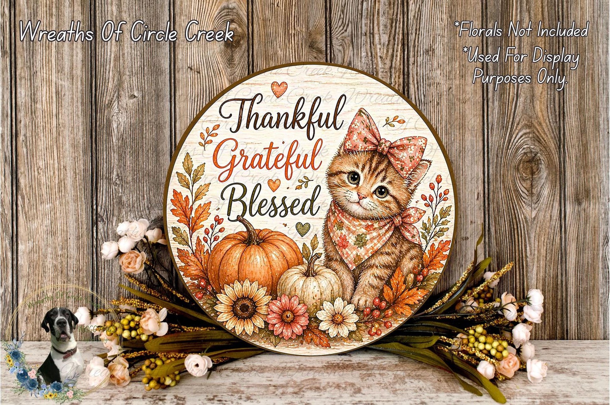 A decorative wooden plaque with a cat and autumn-themed elements, such as pumpkins and flowers, sits on a wooden surface.