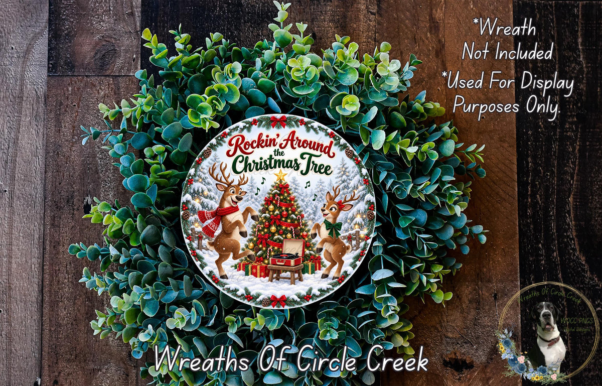 A wreath made of evergreen branches and a Christmas tree, with two reindeer and a snowman as decorative elements. The wreath is displayed on a wooden surface.