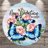 a circular design with a floral theme, including blue butterflies and pink flowers. The text "New Creation in Christ" is written above the floral design.