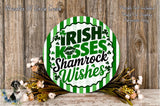 a circular sign with the text "Irish Kisses Shamrock Wishes" surrounded by a floral arrangement and a wooden background.
